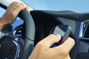 closeup of a man using a smartphone while driving a car