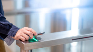 Male hand using smartphone to open automatic gate machine in office building